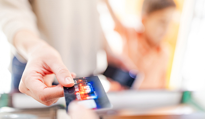 A consumer at a checkout paying with a credit card.